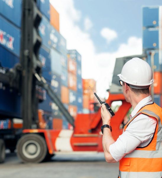 industrial worker is controlling container loading by walkie tal